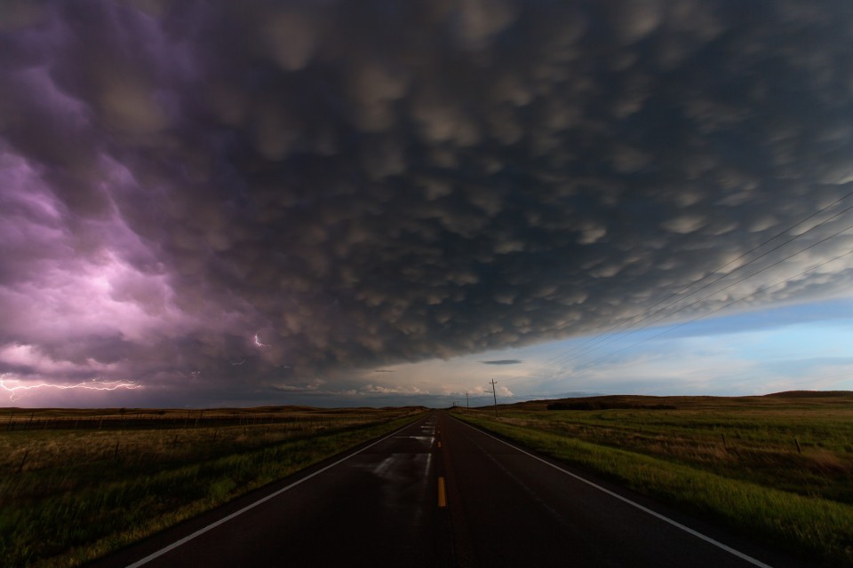 On a long, lonely highway between Marriman and Hyannis, Nebraska...a huge MCS moves by, leaving behind it wet roads and a gorgeous sky filled with mammatus clouds. A bit of lightning snakes around on the left side of the storm.