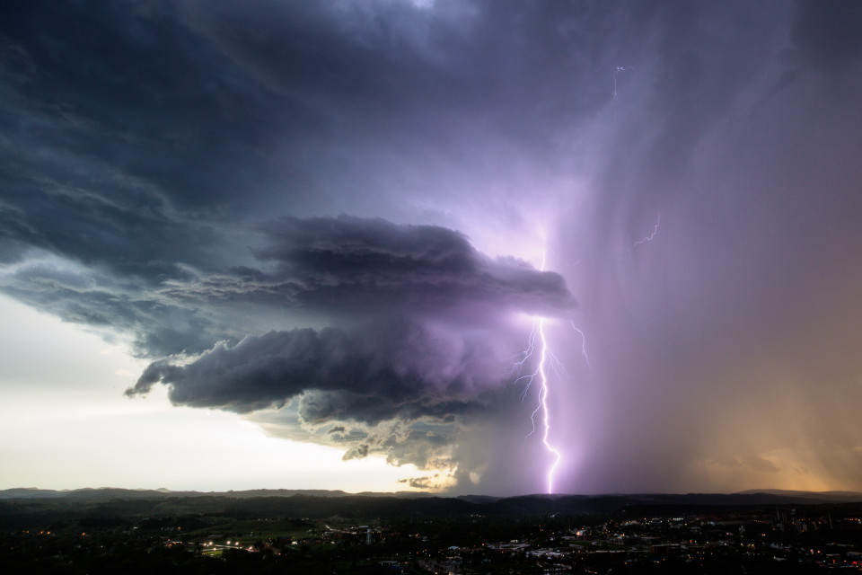 A decaying supercell hovers over the Rapid City, South Dakota area, dropping rain and gorgeous lightning bolts.