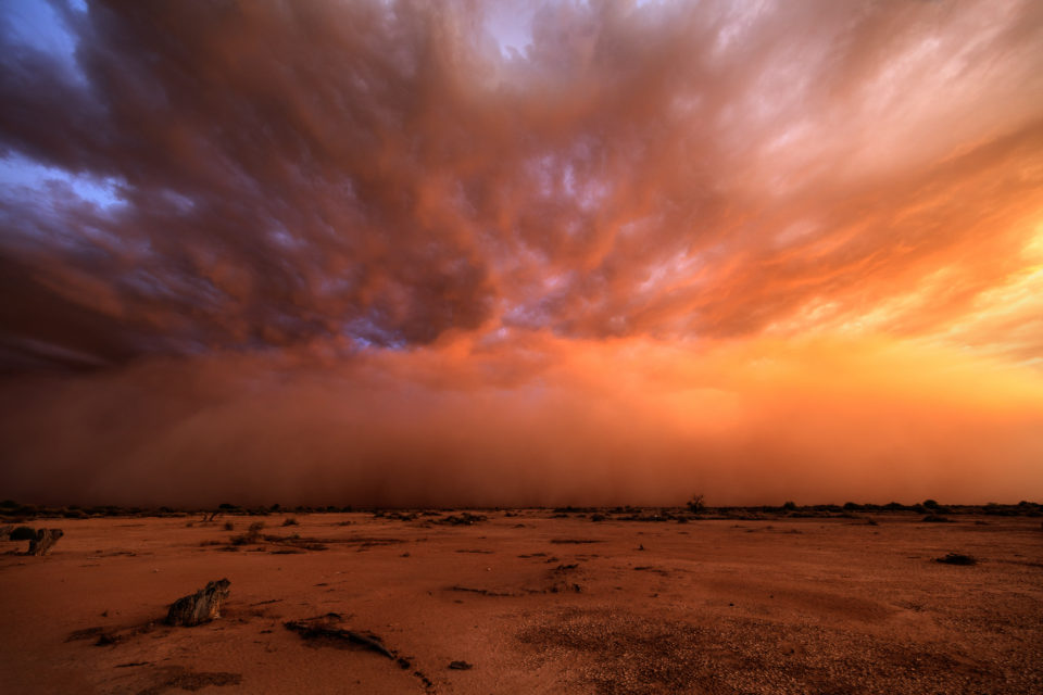 A late season haboob rolls towards Phoenix with the setting sun turning the dust and clouds all shades of purple and orange.